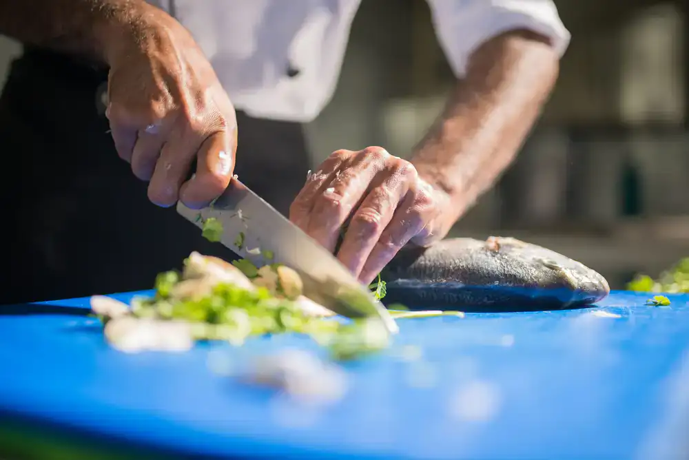 Chef carefully placing herbs on a finished fish dish